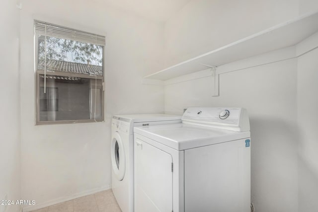 clothes washing area with washing machine and dryer and light tile patterned floors