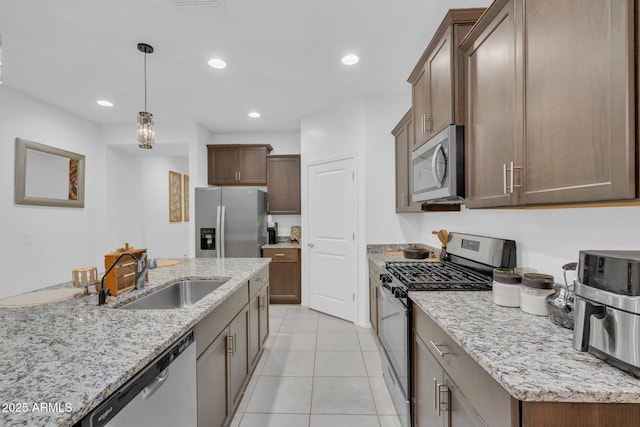 kitchen featuring recessed lighting, light stone countertops, appliances with stainless steel finishes, and a sink