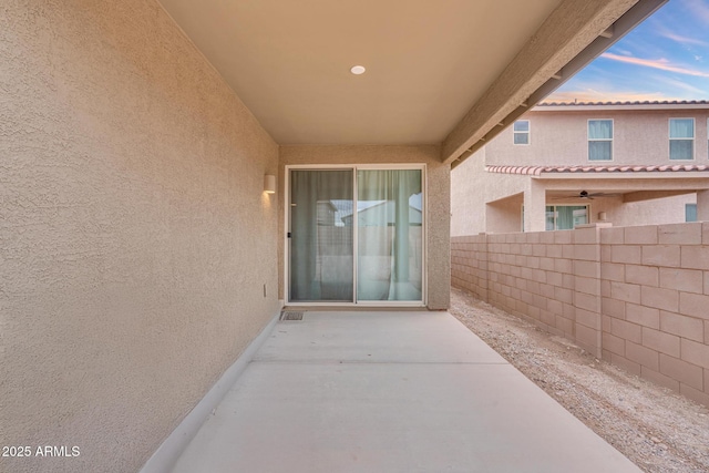 exterior entry at dusk featuring visible vents, stucco siding, a patio, and fence