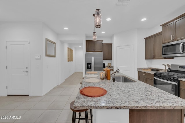 kitchen with visible vents, a sink, dark brown cabinetry, appliances with stainless steel finishes, and light tile patterned floors