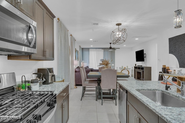 kitchen with visible vents, a sink, dark brown cabinets, appliances with stainless steel finishes, and decorative light fixtures