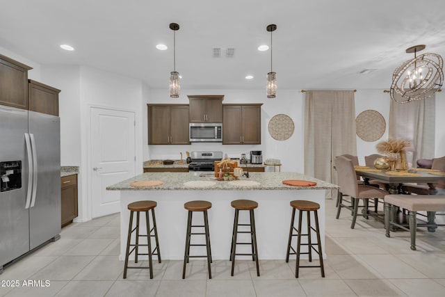 kitchen featuring dark brown cabinets, visible vents, a breakfast bar area, and stainless steel appliances