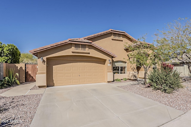 mediterranean / spanish home featuring stucco siding, driveway, a garage, and fence