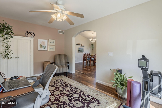 office space featuring a ceiling fan, wood finished floors, visible vents, baseboards, and arched walkways