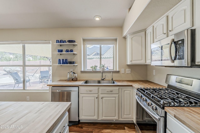 kitchen featuring a sink, white cabinets, wooden counters, and stainless steel appliances