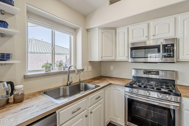 kitchen with open shelves, a sink, butcher block countertops, appliances with stainless steel finishes, and white cabinetry