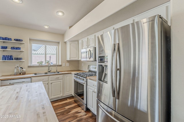 kitchen with recessed lighting, dark wood-style flooring, a sink, stainless steel appliances, and white cabinets