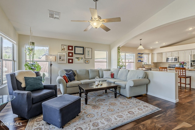 living room with visible vents, a healthy amount of sunlight, dark wood-style flooring, and vaulted ceiling