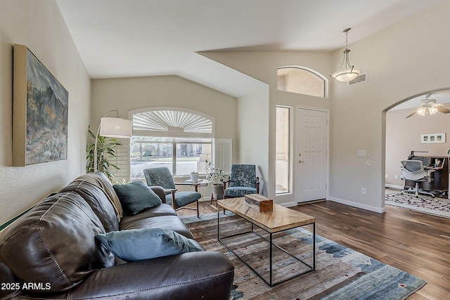 living room with visible vents, wood finished floors, arched walkways, baseboards, and vaulted ceiling