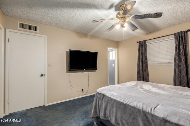 bedroom featuring dark colored carpet, a textured ceiling, and ceiling fan