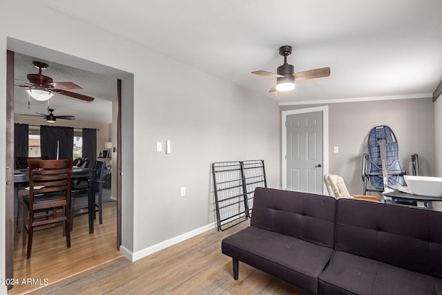 living room featuring ceiling fan, wood-type flooring, and ornamental molding