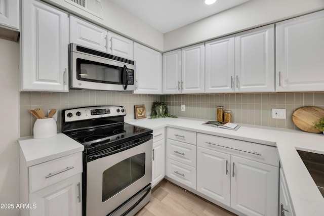 1717 E Union Hills Dr Unit 1033, Phoenix, AZ 85024 - kitchen with stainless steel appliances, white cabinetry, light countertops, decorative backsplash, and light wood-style flooring
