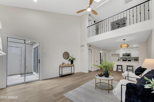 1717 E Union Hills Dr Unit 1033, Phoenix, AZ 85024 - living area with light wood-type flooring, a towering ceiling, a ceiling fan, and baseboards