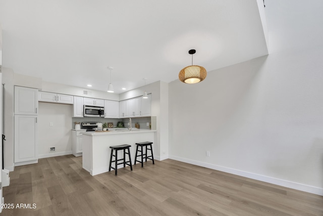 1717 E Union Hills Dr Unit 1033, Phoenix, AZ 85024 - kitchen featuring appliances with stainless steel finishes, white cabinets, a peninsula, baseboards, and light wood-style flooring