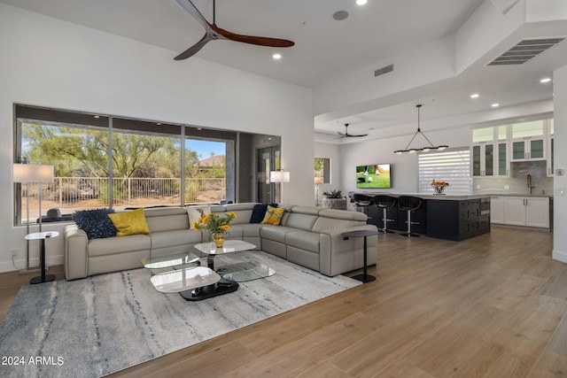 living area with light wood finished floors, ceiling fan with notable chandelier, visible vents, and recessed lighting