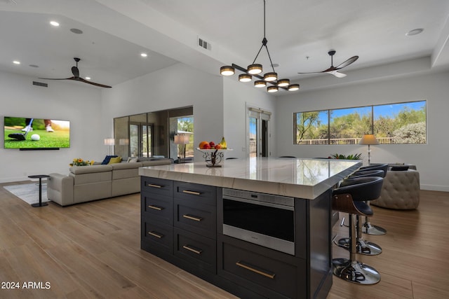 kitchen featuring visible vents, wood finished floors, a ceiling fan, and open floor plan