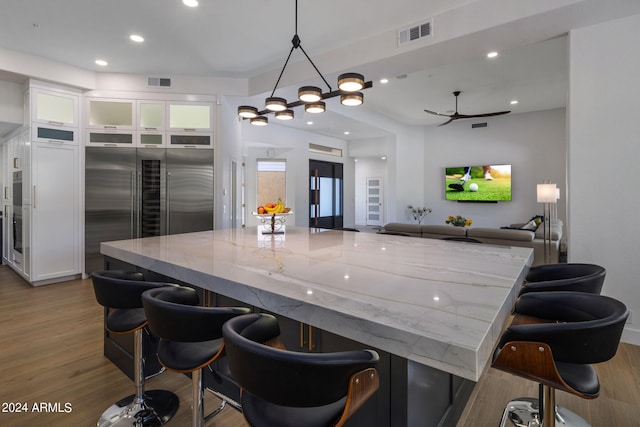kitchen with white cabinets, visible vents, light stone countertops, and wood finished floors