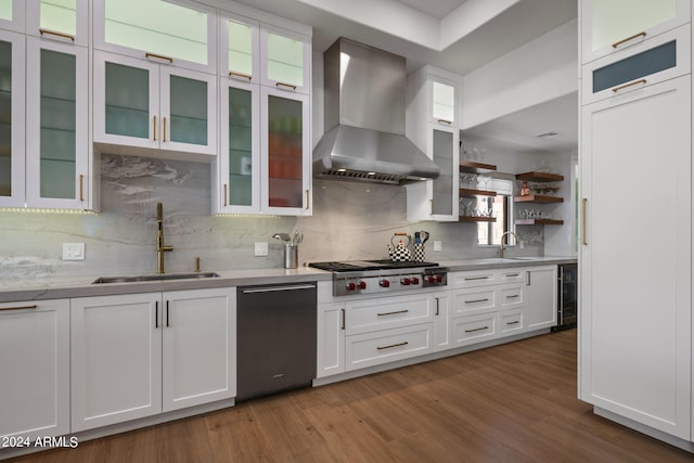 kitchen with a sink, white cabinetry, wood finished floors, stainless steel gas stovetop, and wall chimney range hood