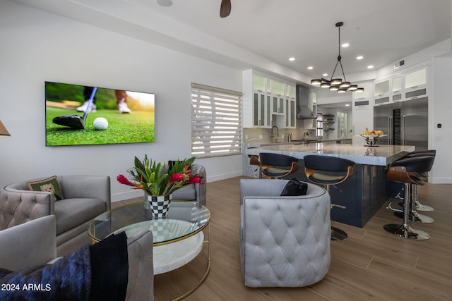 interior space with a large island, wall chimney exhaust hood, hardwood / wood-style flooring, and decorative light fixtures