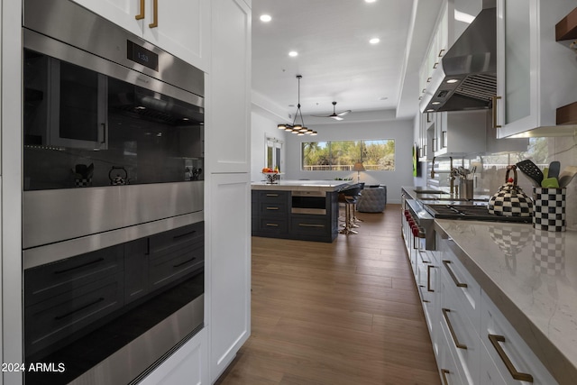 kitchen featuring ventilation hood, tasteful backsplash, dark wood finished floors, white cabinets, and oven