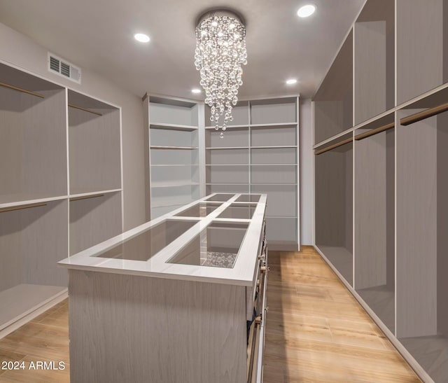 walk in closet with an inviting chandelier and light hardwood / wood-style flooring