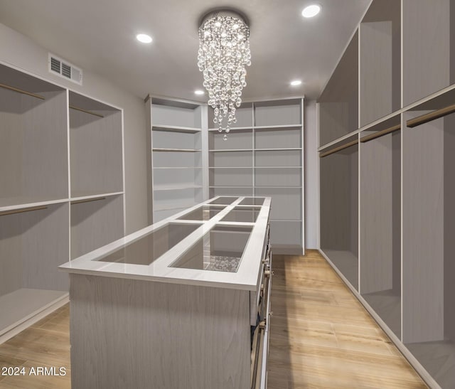 walk in closet featuring an inviting chandelier, light wood-style flooring, and visible vents