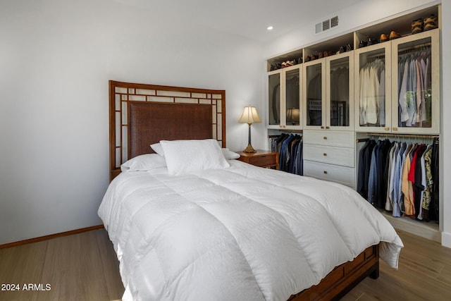 bedroom featuring baseboards, visible vents, and wood finished floors