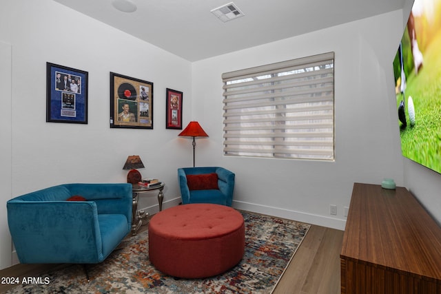 living area with baseboards, visible vents, and wood finished floors