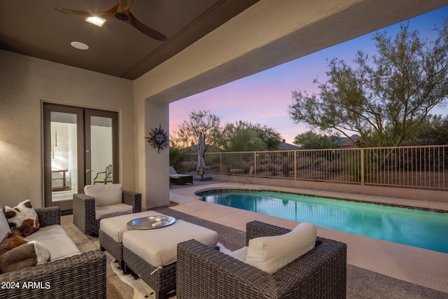 pool at dusk with a patio area, outdoor lounge area, and ceiling fan