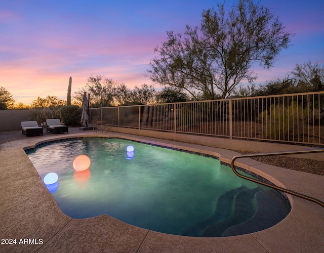 pool at dusk with an outdoor living space and a patio area