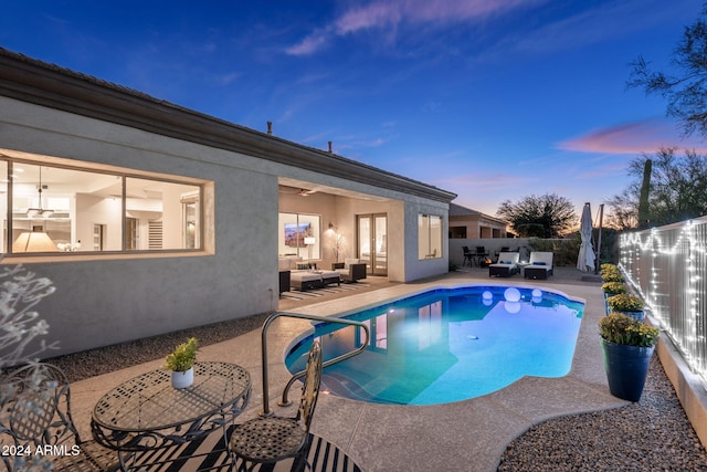 pool at dusk with a fenced backyard, a fenced in pool, an outdoor living space, and a patio area