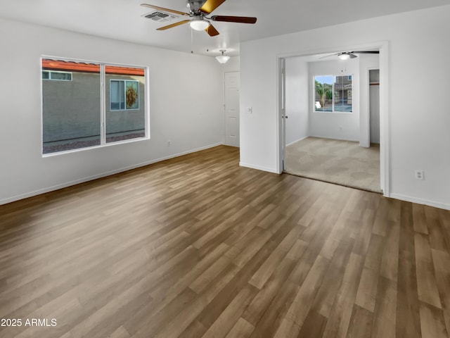 interior space with a ceiling fan, wood finished floors, visible vents, and baseboards