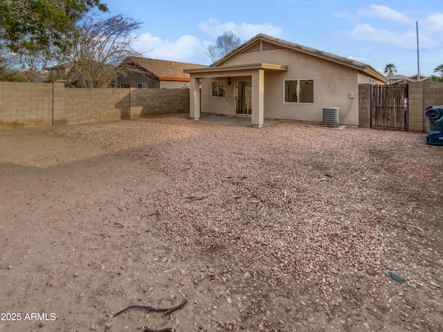 back of property featuring a patio, central AC unit, a fenced backyard, a gate, and stucco siding