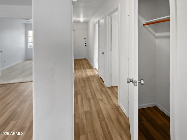 hall with light wood-style flooring and baseboards