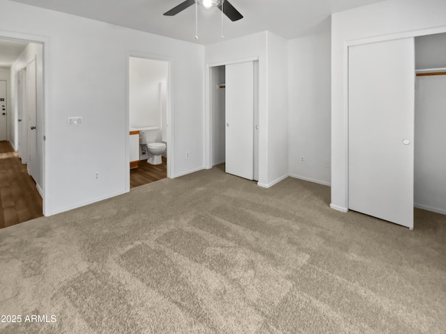 unfurnished bedroom featuring ceiling fan, connected bathroom, carpet flooring, baseboards, and multiple closets