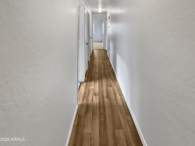 hall featuring baseboards and wood finished floors