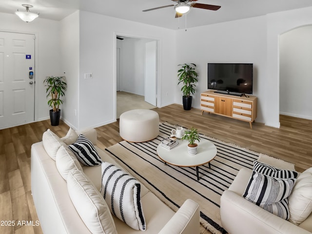 living area with ceiling fan, arched walkways, wood finished floors, and baseboards