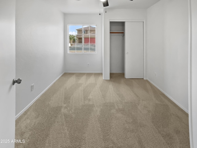 unfurnished bedroom featuring carpet floors, a ceiling fan, baseboards, and a closet