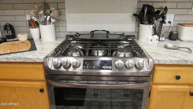 room details featuring light stone countertops, gas stove, and tasteful backsplash