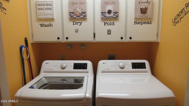 laundry room featuring washer and clothes dryer and cabinets