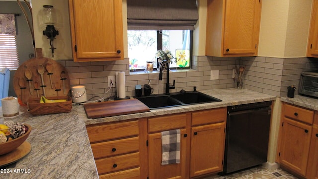 kitchen featuring decorative backsplash, sink, light stone counters, and black dishwasher