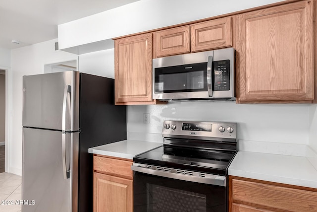 kitchen featuring light brown cabinets, light tile patterned floors, and stainless steel appliances