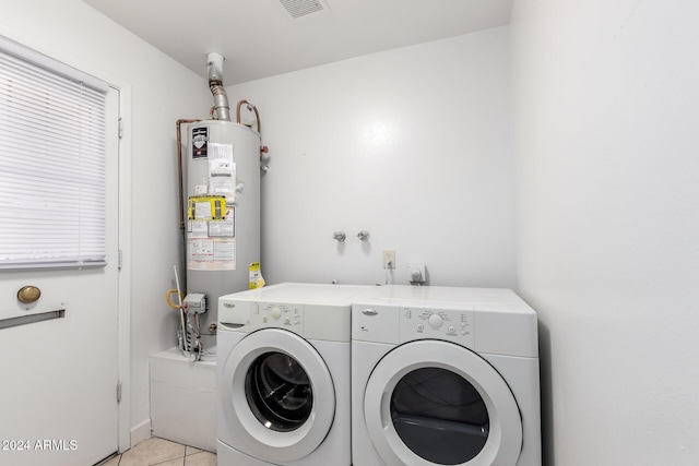 laundry area with water heater, light tile patterned flooring, and washer and dryer