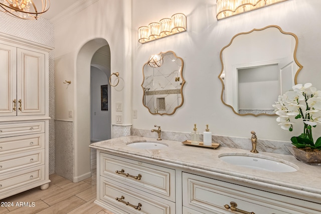 bathroom with a notable chandelier, vanity, crown molding, and hardwood / wood-style floors