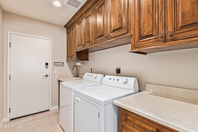 laundry room featuring light hardwood / wood-style floors, washing machine and dryer, sink, and cabinets