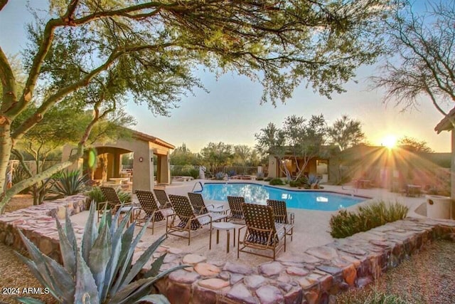 pool at dusk featuring a patio