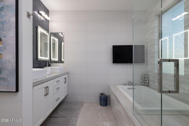 full bathroom featuring tile walls, tile patterned flooring, a bath, and vanity
