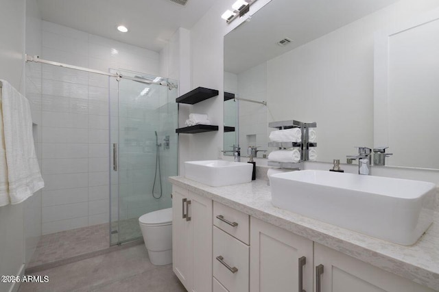 full bath featuring visible vents, a stall shower, double vanity, and a sink