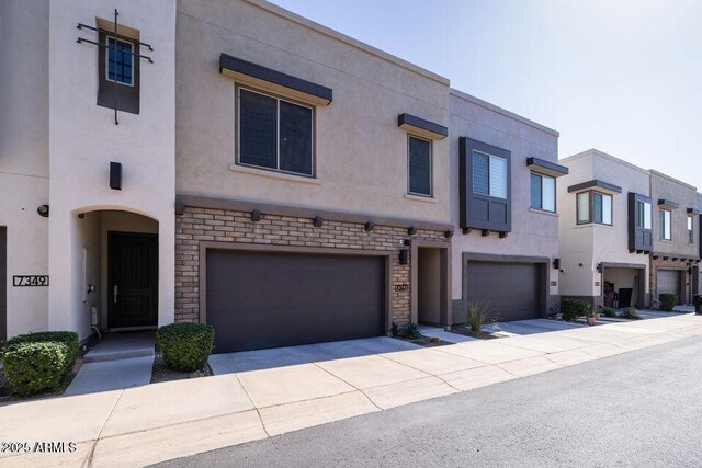 view of front facade with stone siding, stucco siding, driveway, and an attached garage