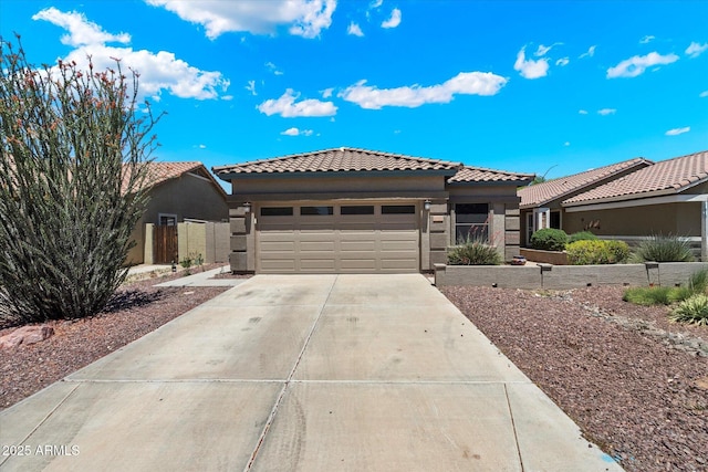 view of front of home with a tiled roof, an attached garage, driveway, and stucco siding